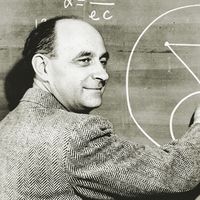 Italian-born physicist Dr. Enrico Fermi draws a diagram at a blackboard with mathematical equations. circa 1950.
